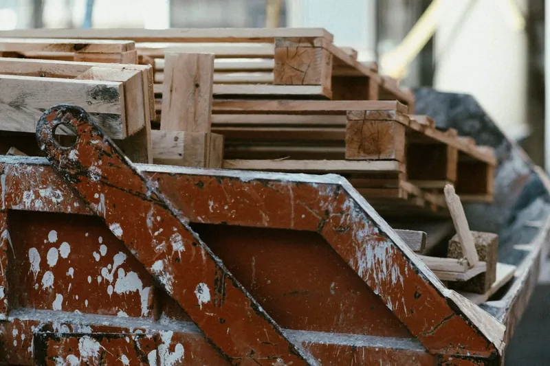 Rusty dumpster filled with wooden pallets next to a building
